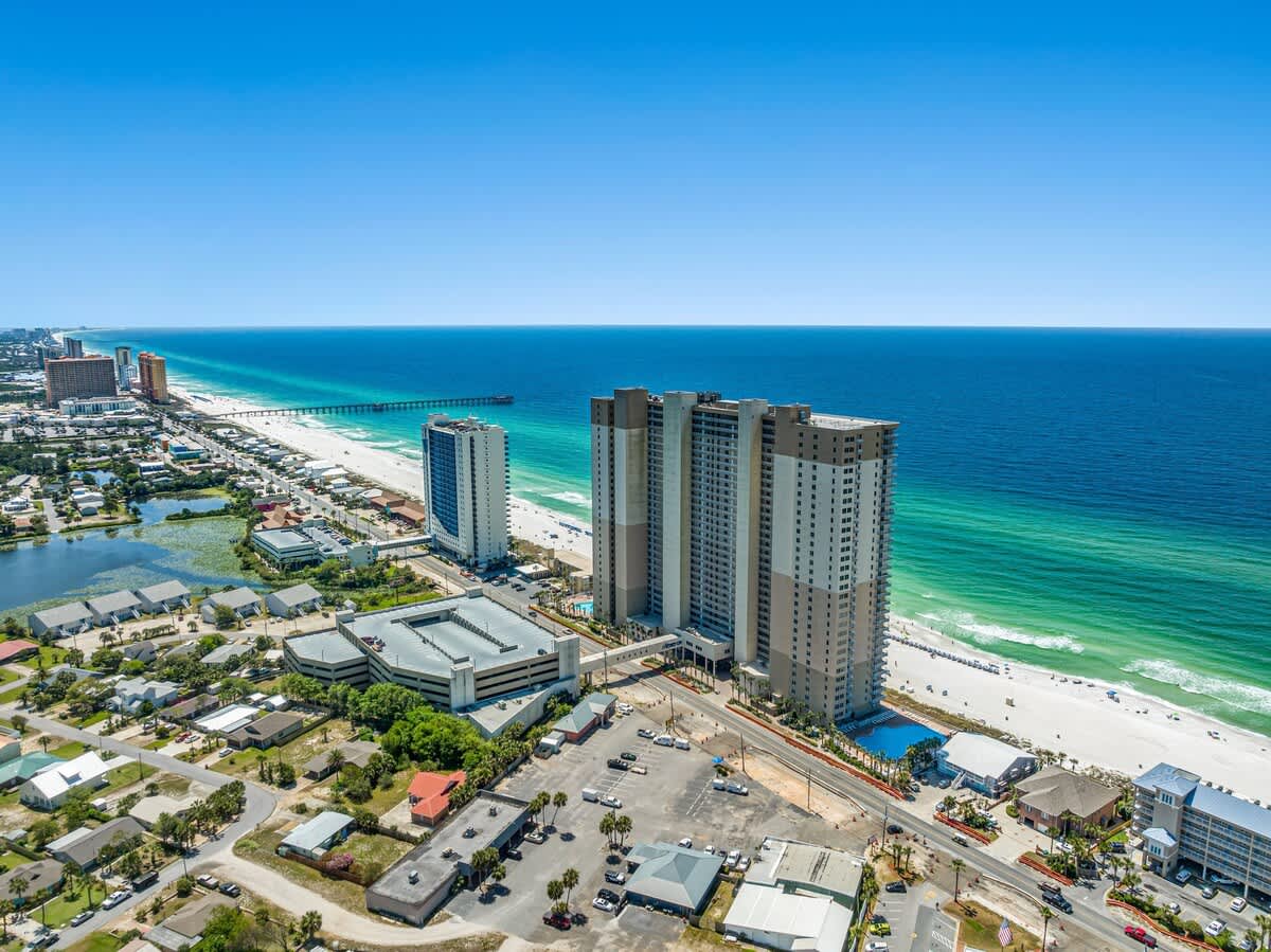 Tidewater 2615 – Aerial view of Tidewater 2615, beachfront condos near a pier and clear blue ocean.