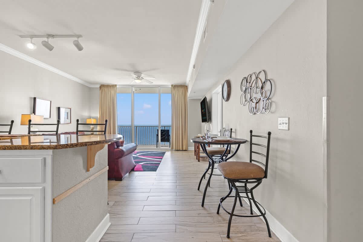 Tidewater 2615 – Living room with ocean view, kitchenette, seating area, and small dining table.