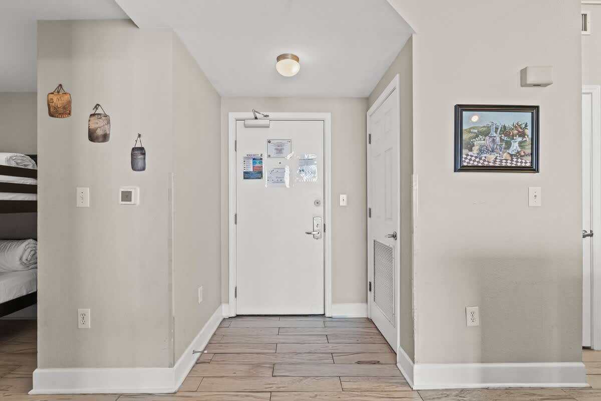 Tidewater 2615 – Entryway of a vacation rental with bunk beds, wall decor, and door leading outside.