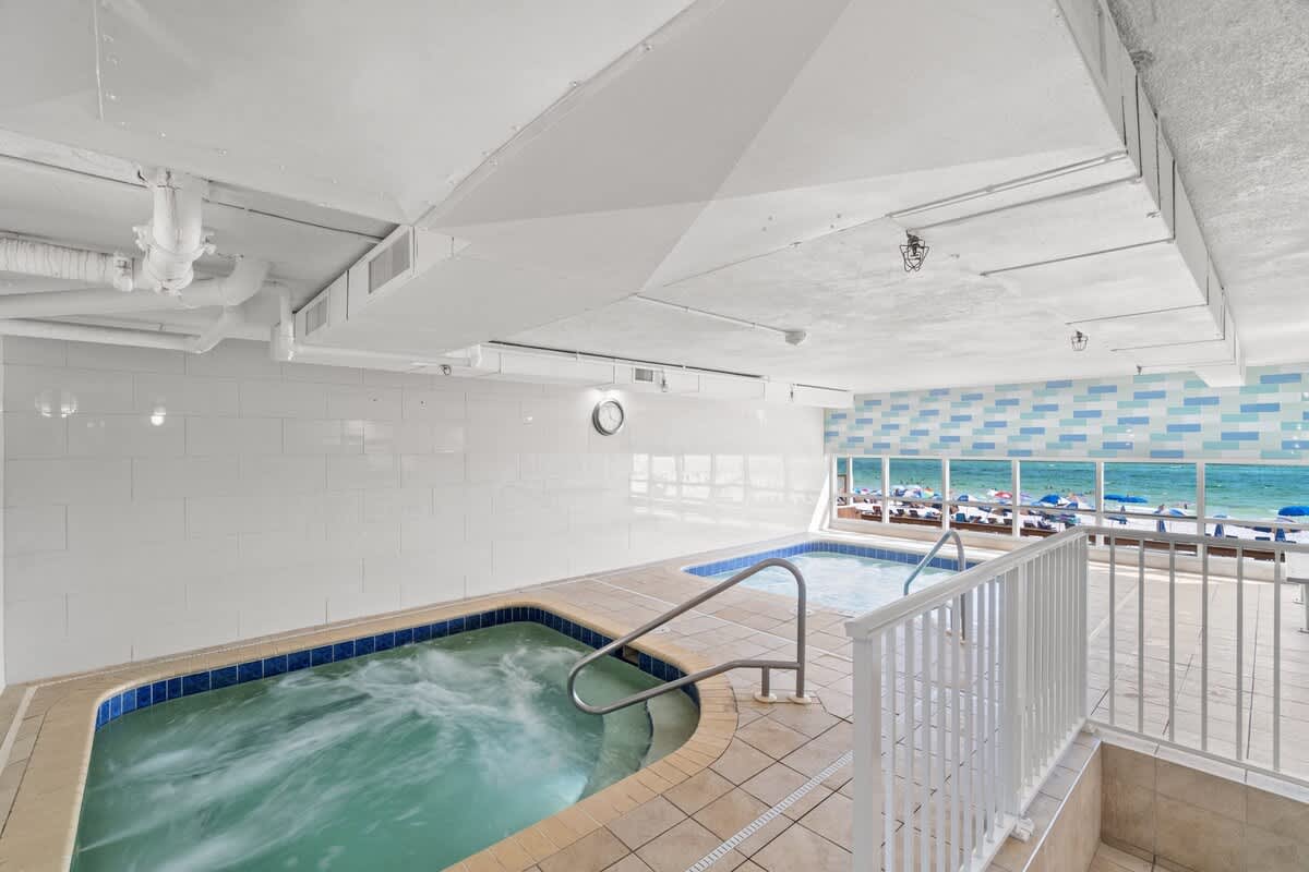 Tidewater 2615 – Indoor pool area with hot tubs and ocean view through large windows.