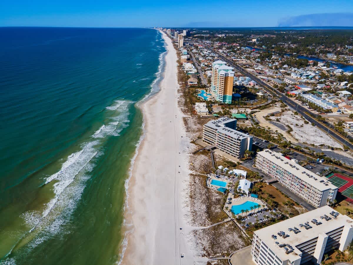 Dunes C605 – Aerial view of a beach with condominiums, pools, and sandy shoreline along the coast.
