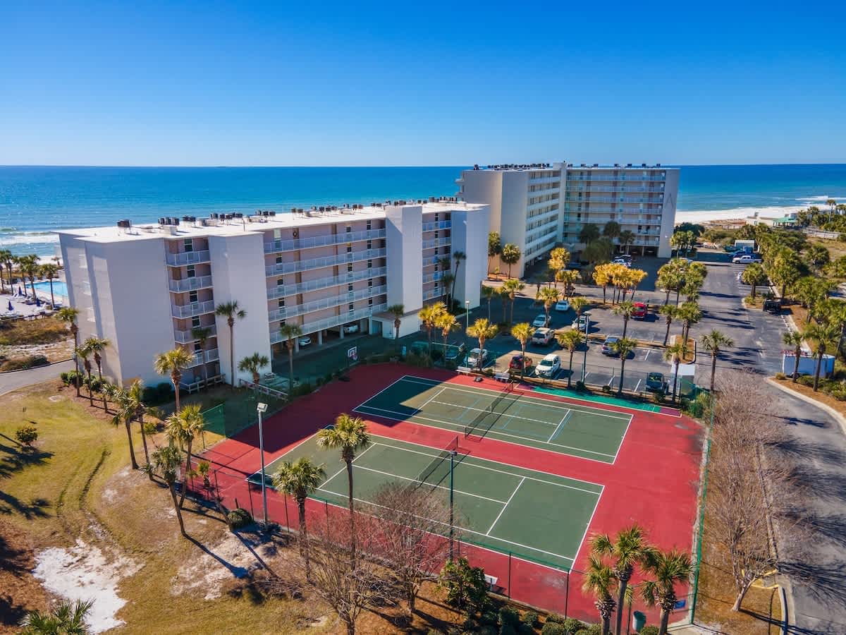 Dunes C605 – Aerial view of Dunes C605 with tennis courts and ocean in the background.