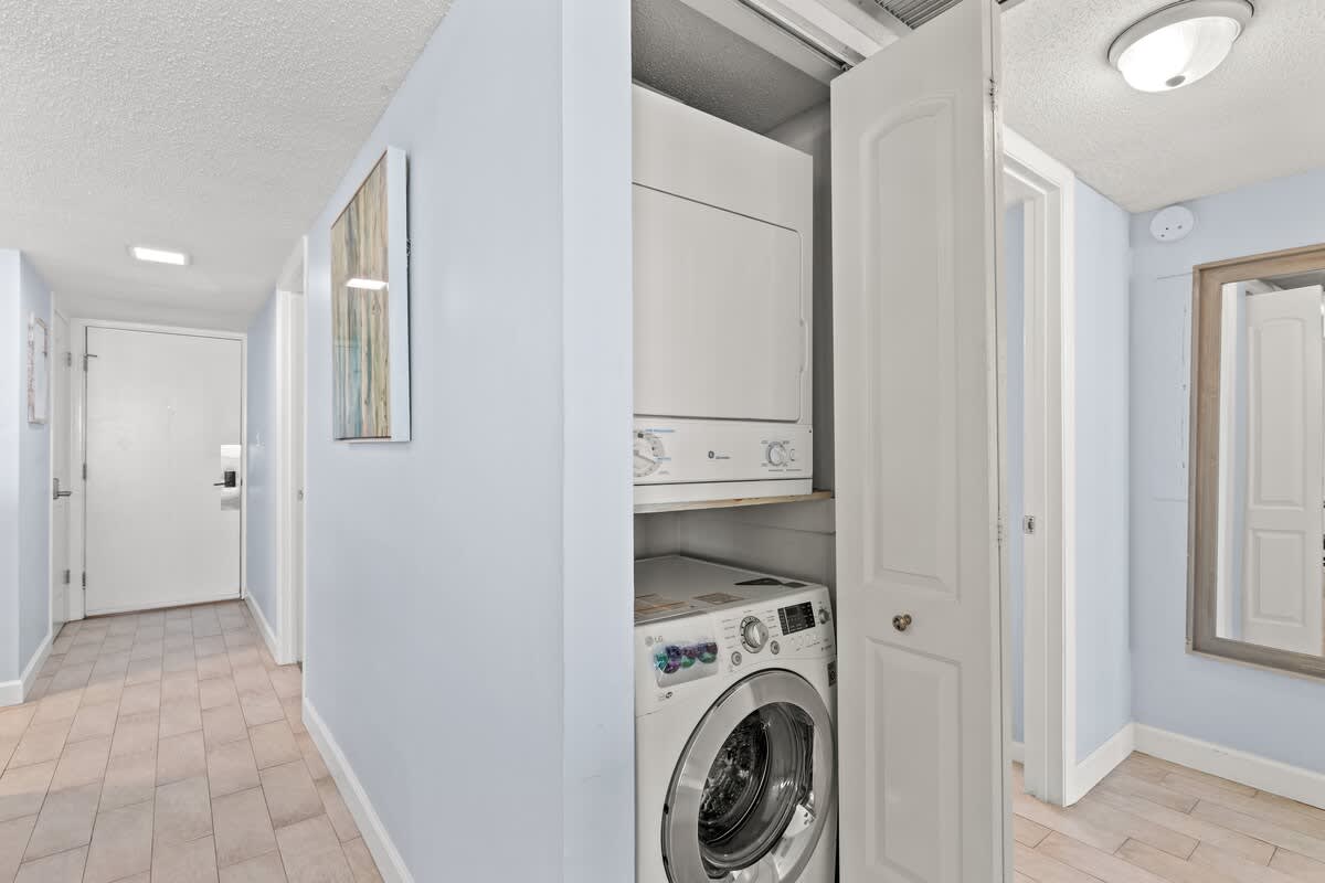 Dunes C605 – Laundry area with stacked washer and dryer, light blue walls, and tiled floor.
