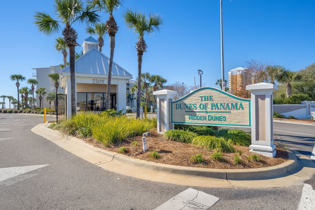Dunes C605 – Entrance sign of Dunes of Panama with palm trees and a white building in the background.