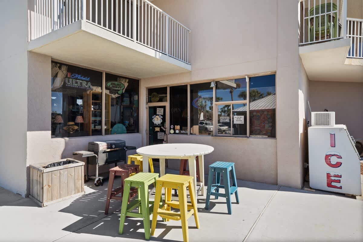 Dunes C605 – Outdoor seating with colorful stools near a store entrance and an ice vending machine.