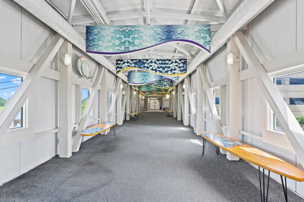 Tidewater 200 – Long, bright corridor with decorative ceiling and tables on either side, featuring large windows.