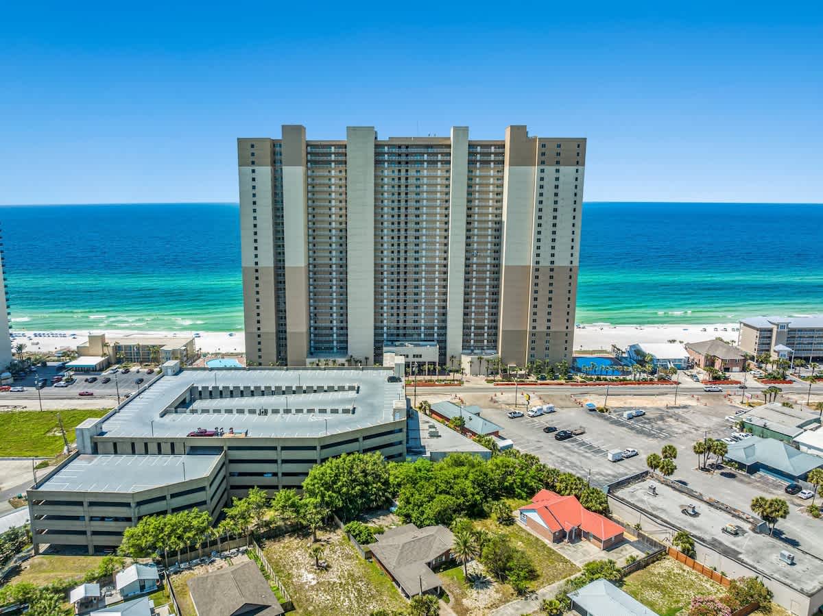 Tidewater 200 – Tall beachfront condominium with ocean view, nearby parking garage, and surrounding green areas.