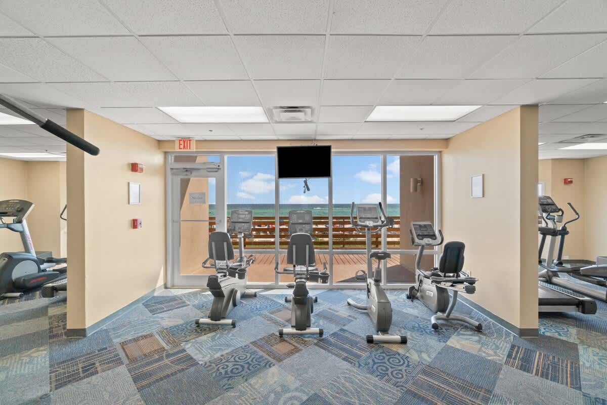 Tidewater 200 – Gym area with exercise equipment and large windows showing a seaside view.