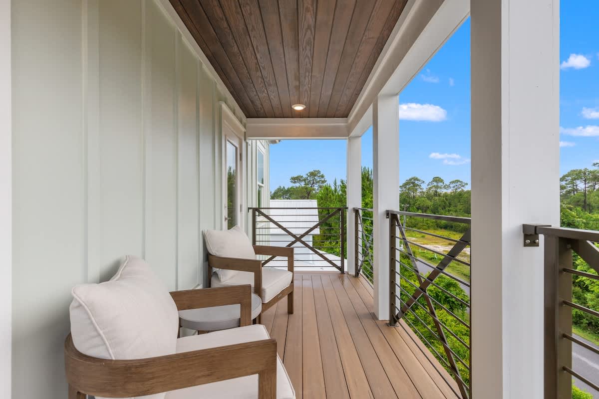 224 W Willow Mist Rd – Covered balcony with wooden flooring, two armchairs, and views of trees and road.