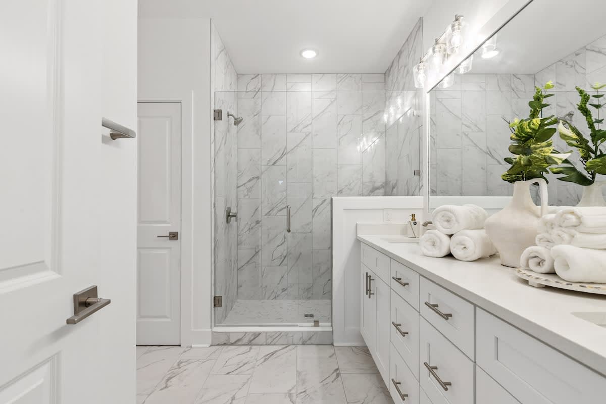 224 W Willow Mist Rd – Modern bathroom with marble walls, glass shower, double vanity, and neatly rolled towels.