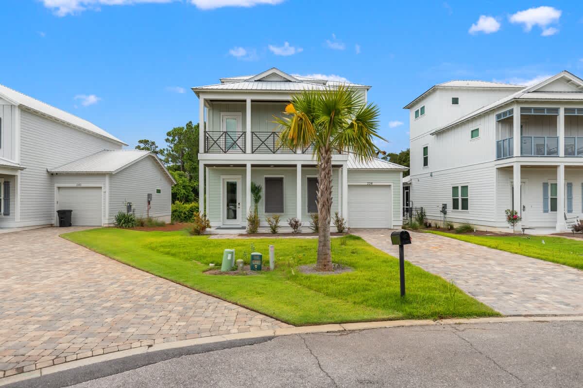 224 W Willow Mist Rd – Two-story white house with a palm tree, grassy yard, and paved driveway.