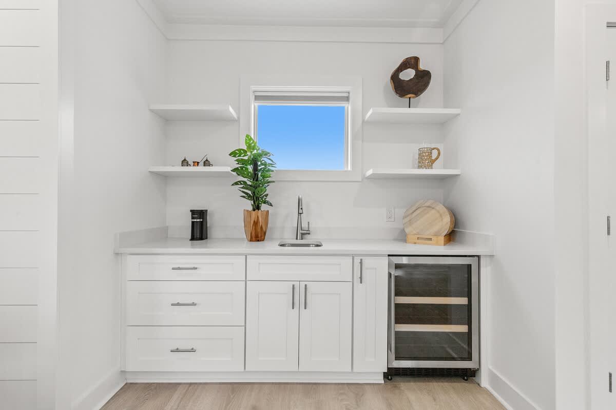 224 W Willow Mist Rd – Modern kitchenette with white cabinetry, shelves, sink, coffee maker, and wine fridge, featuring a window view.