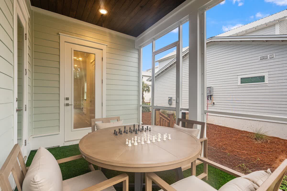 224 W Willow Mist Rd – Covered porch with a round table, two chairs, and a chess set, overlooking neighboring houses and greenery.