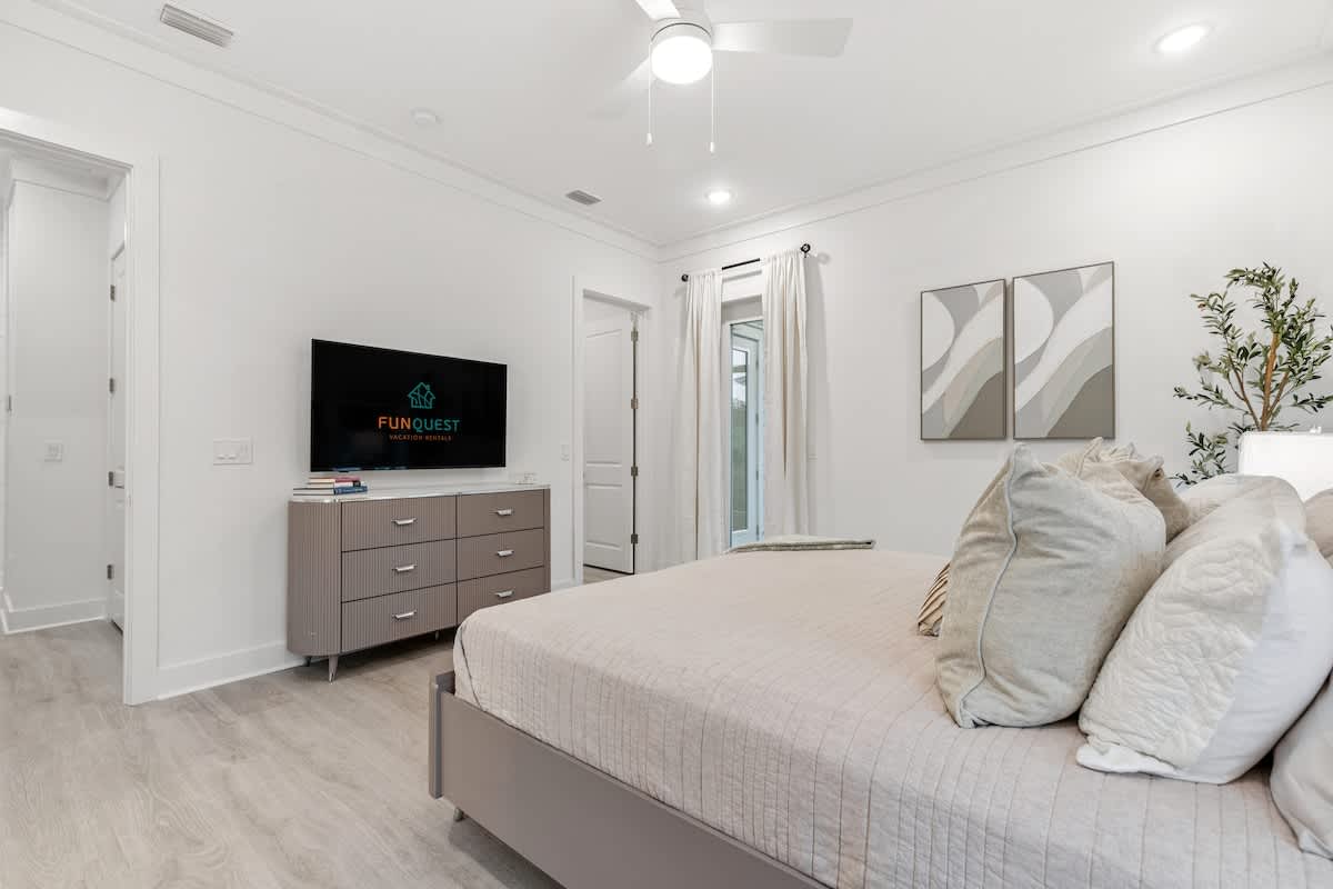 224 W Willow Mist Rd – Bright bedroom with a bed, TV, dresser, and outdoor view through curtains.