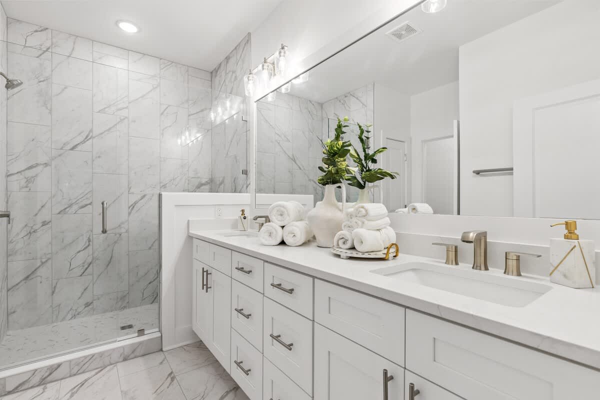 224 W Willow Mist Rd – Modern bathroom with marble walls, glass shower, double sink vanity, and neatly arranged towels.