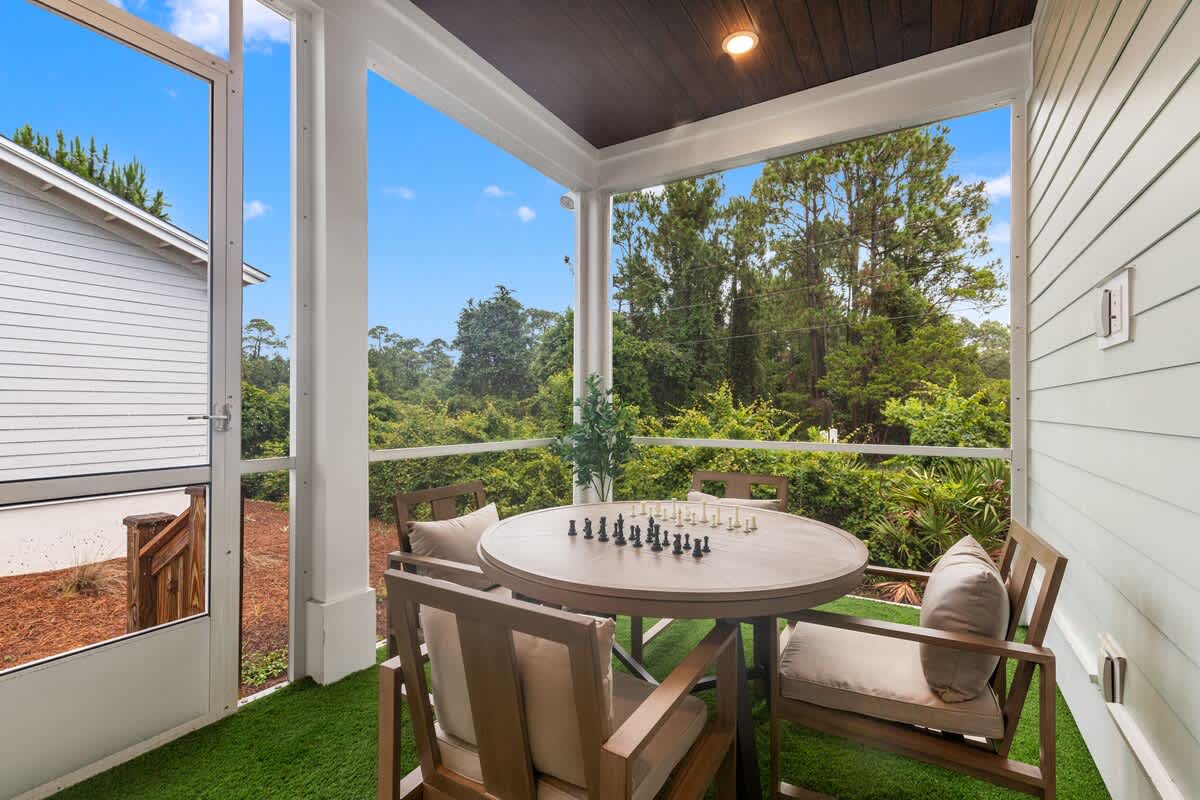 224 W Willow Mist Rd – Screened porch with table and chairs, chess set, and view of greenery.