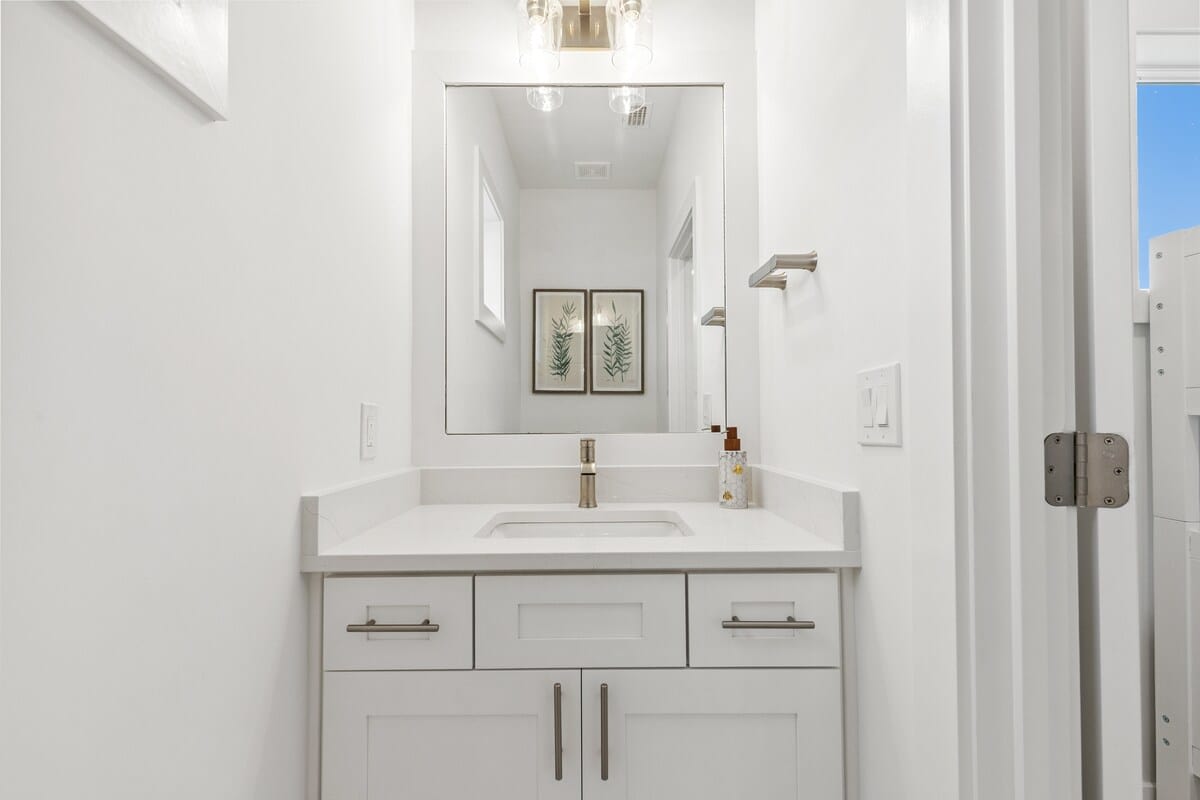 224 W Willow Mist Rd – Bright white bathroom with sink, mirror, and light fixtures; framed botanical art on the wall.