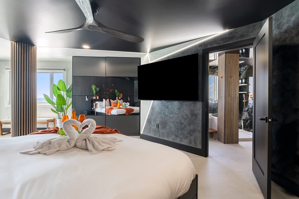 The Summit Penthouse 1501 – Luxury bedroom with a king-size bed, modern decor, large TV, and a view window.