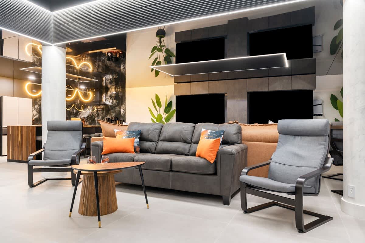 The Summit Penthouse 1501 – Modern living area with a gray sofa, accent chairs, wooden coffee table, and stylish lighting.