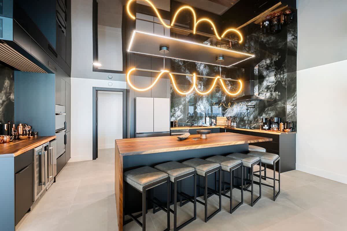 The Summit Penthouse 1501 – Modern kitchen with a large wood island, sleek cabinetry, pendant lighting, and seating for six.