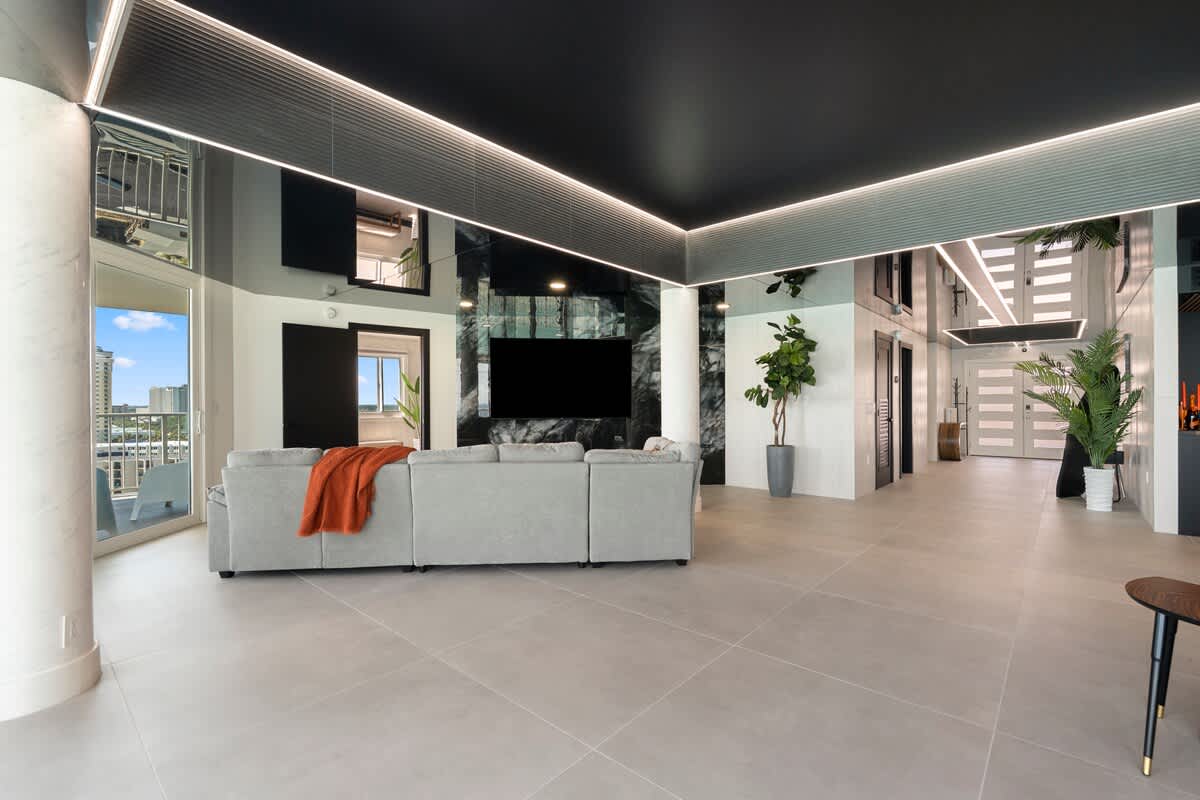 The Summit Penthouse 1501 – Spacious living room with a grey sofa, large windows, and modern decor.