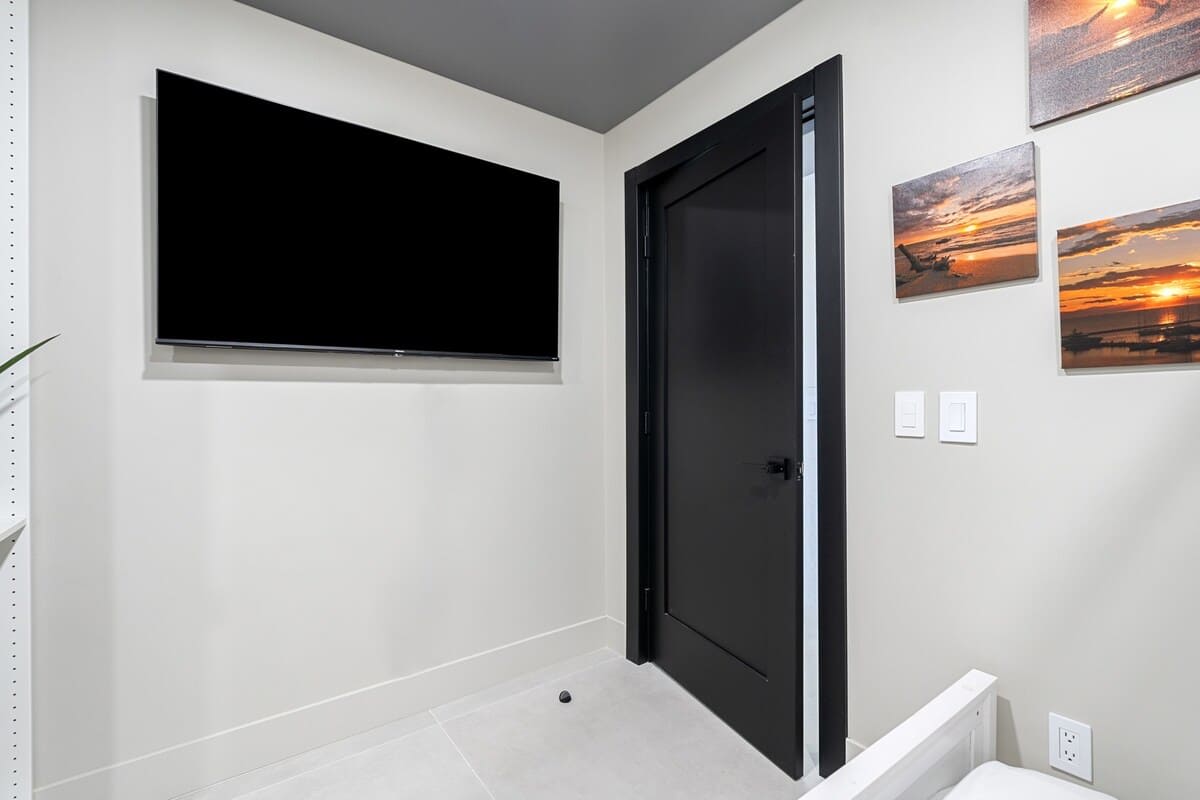 The Summit Penthouse 1501 – Entry hallway featuring a black door, wall-mounted TV, and framed sunset photographs.
