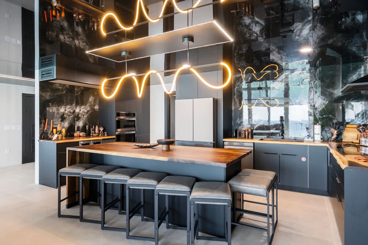 The Summit Penthouse 1501 – Modern kitchen with sleek black cabinets, a wooden island, and stylish pendant lighting.