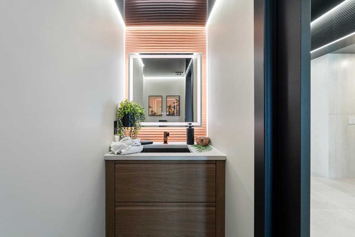 The Summit Penthouse 1501 – Modern bathroom with a sink, mirror, plants, and soft lighting.