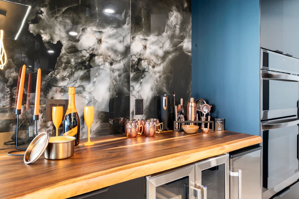 The Summit Penthouse 1501 – Modern kitchen with dark marble backsplash, wooden counter, and various beverage accessories.