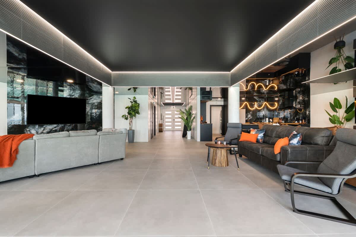 The Summit Penthouse 1501 – Open living area with modern furniture, large windows, and sleek kitchen, featuring dark accents and bright lighting.