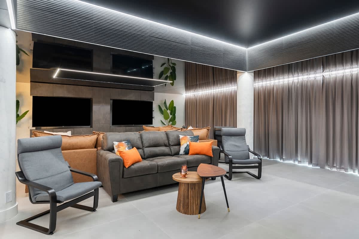 The Summit Penthouse 1501 – Modern living room with a grey couch, accent pillows, and two chairs beside a small wooden table.