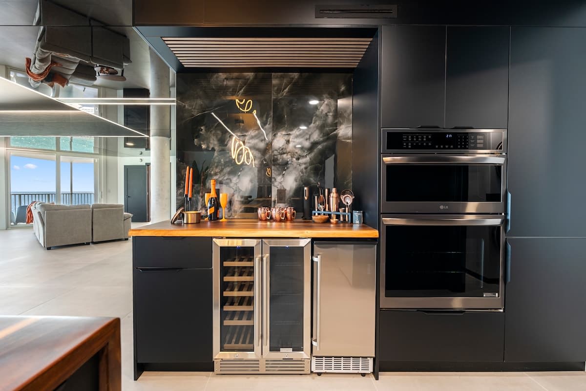 The Summit Penthouse 1501 – Modern kitchen with sleek cabinetry, wine cooler, and a view of the ocean through large windows.