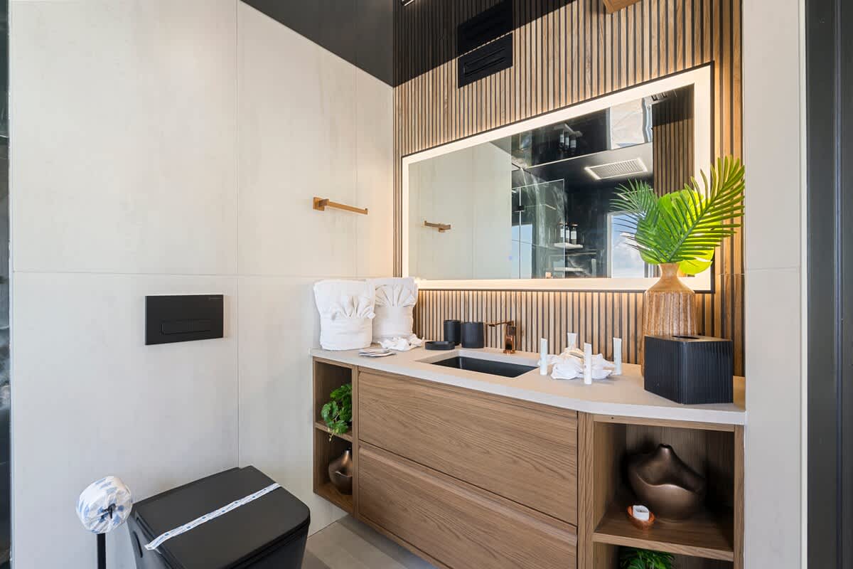 The Summit Penthouse 1501 – Modern bathroom with wooden accents, large mirror, sink, and decorative plants.