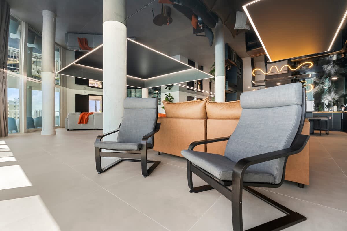 The Summit Penthouse 1501 – Spacious living area with gray chairs, modern decor, and large windows showcasing a city view.