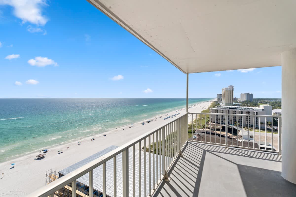 The Summit Penthouse 1501 – Penthouse balcony view of beach, ocean, and nearby buildings under a clear blue sky.