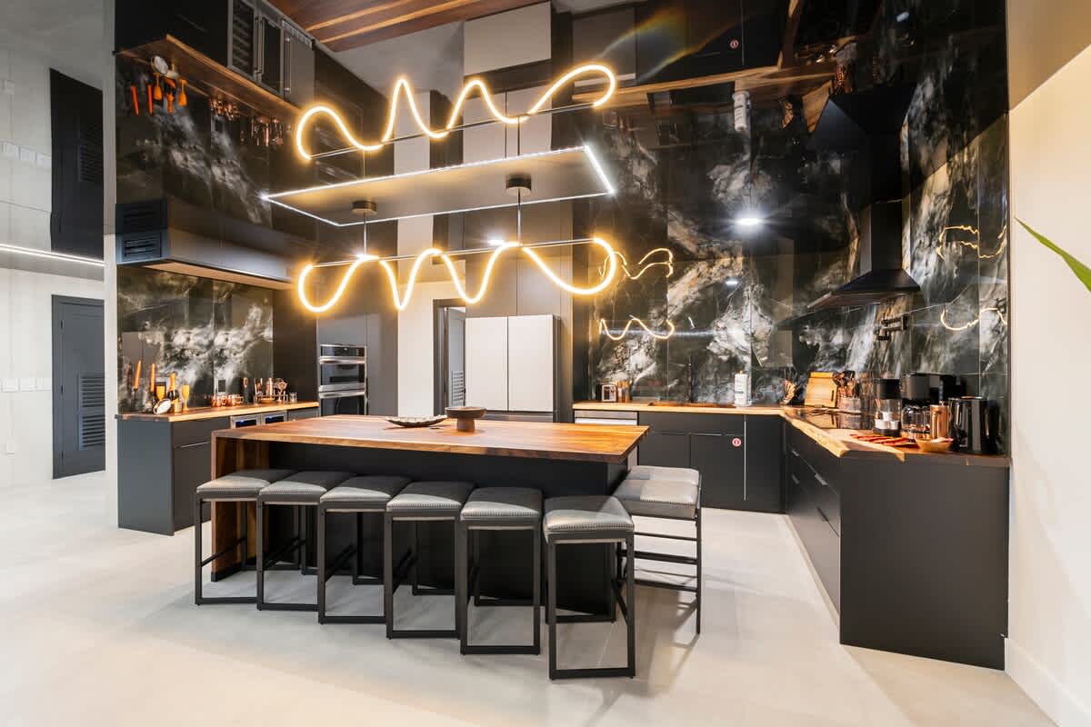 The Summit Penthouse 1501 – Modern kitchen with black cabinetry, large island, and unique overhead lighting. Bar stools along the island.