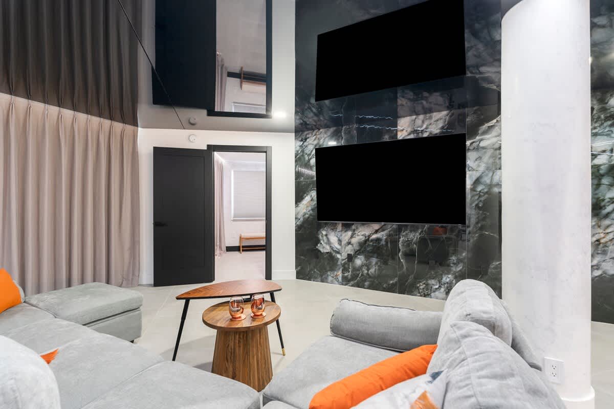 The Summit Penthouse 1501 – Modern living room with gray sectional sofa, wooden coffee table, and wall-mounted screens.