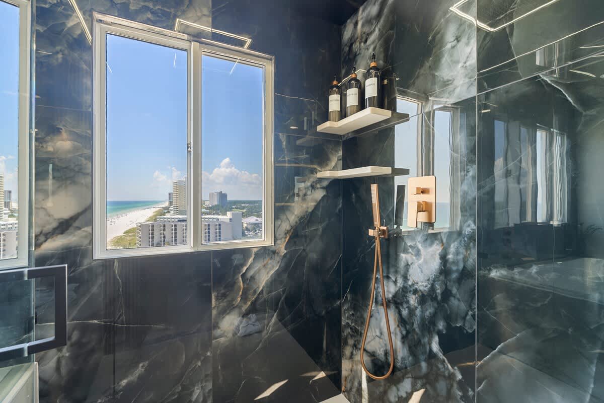 The Summit Penthouse 1501 – Luxury shower with ocean view, featuring marble walls and modern fixtures.