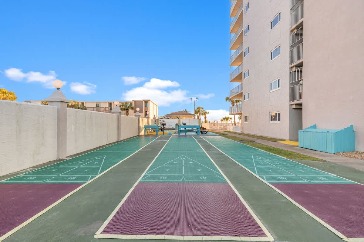 The Summit Penthouse 1501 – Outdoor shuffleboard courts beside a multi-story building with a blue sky in the background.