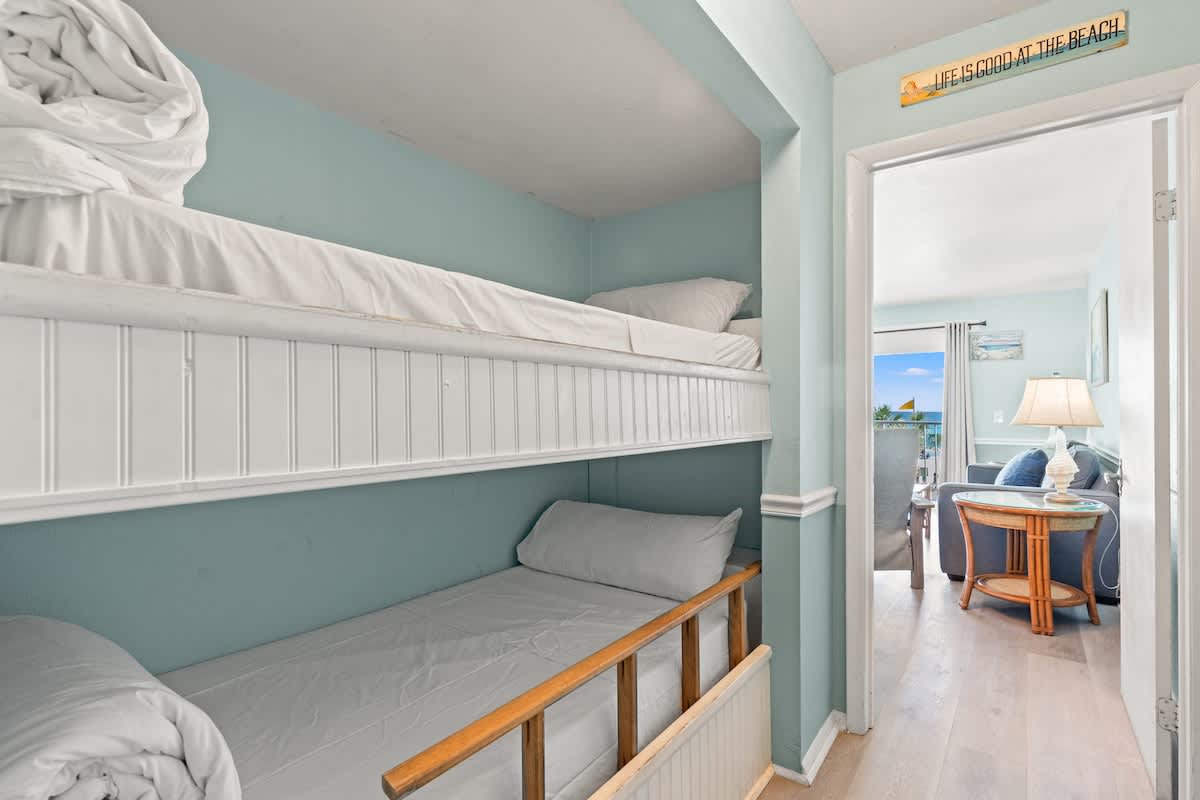 The Summit 315 – Bunk beds in a pastel room with a view of a living area and patio.