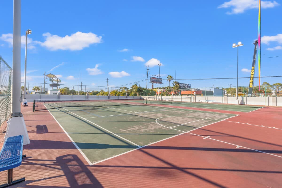 The Summit 315 – Tennis court with a view of nearby attractions and palm trees under a clear blue sky.