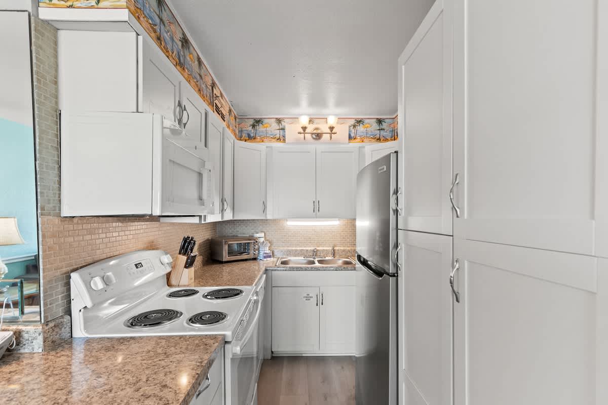 The Summit 315 – Kitchen with white cabinets, granite countertops, and stainless steel appliances, including a stove and refrigerator.