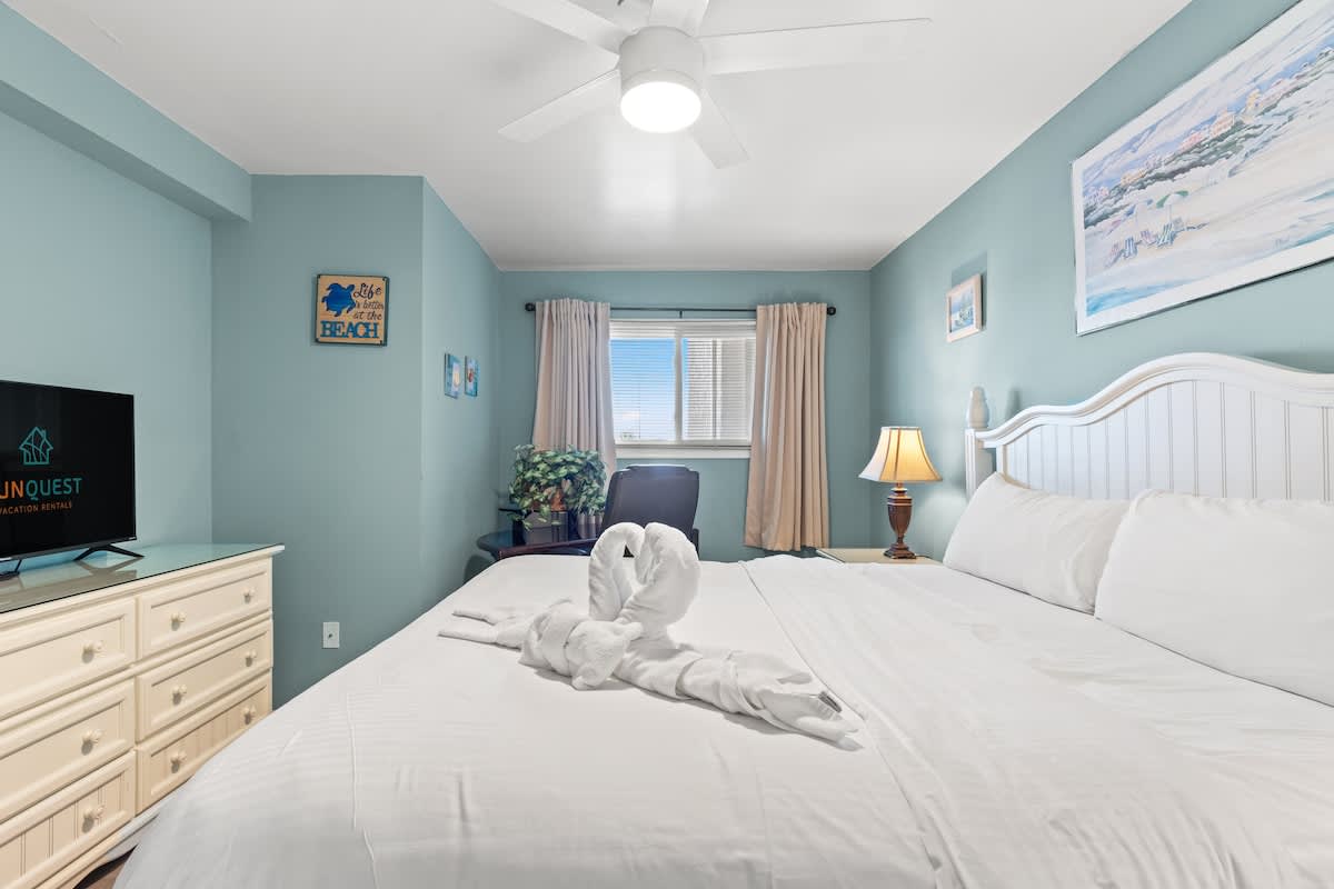 The Summit 315 – Cozy bedroom with a queen bed, dresser, TV, and windows with natural light.