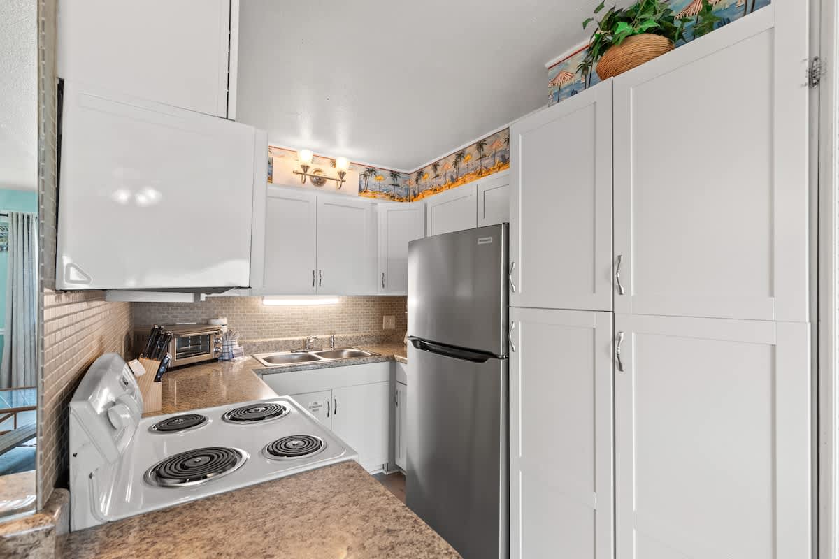 The Summit 315 – Modern kitchen with white cabinets, stainless steel refrigerator, and stone countertop.