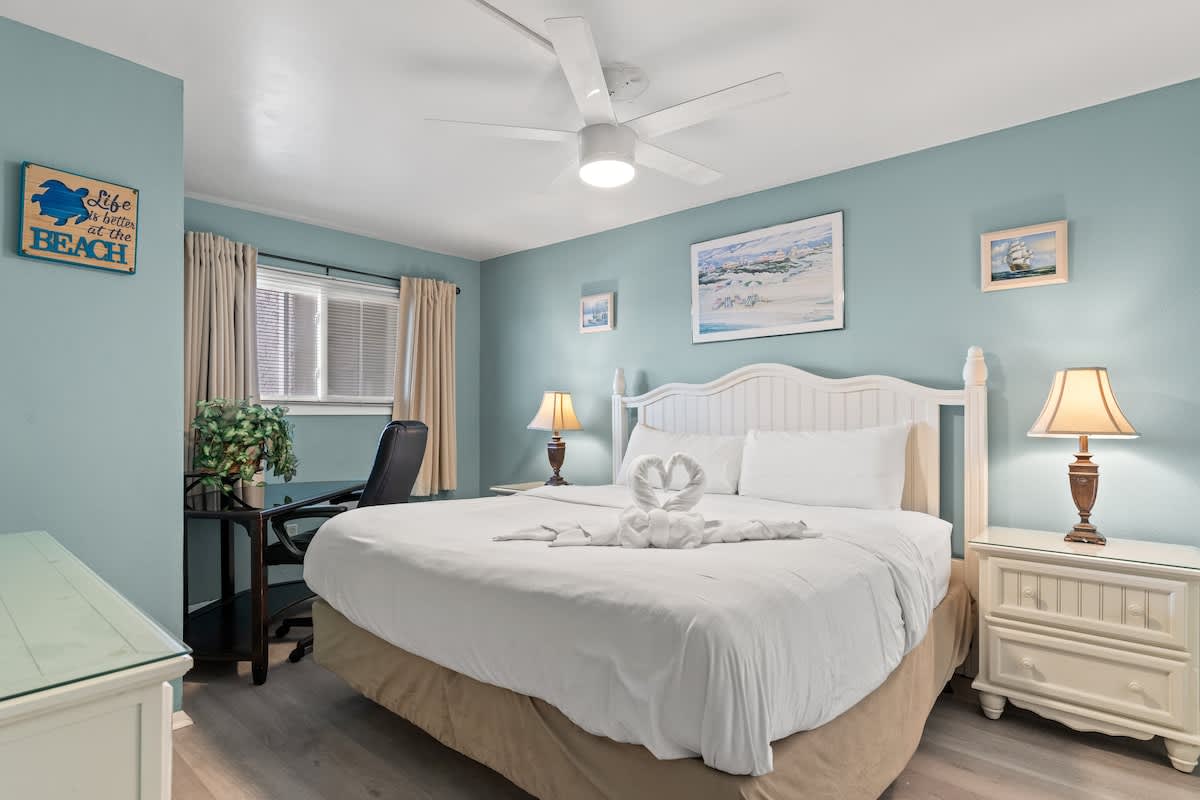 The Summit 315 – Cozy bedroom with a queen bed, desk, and lamps against light blue walls.