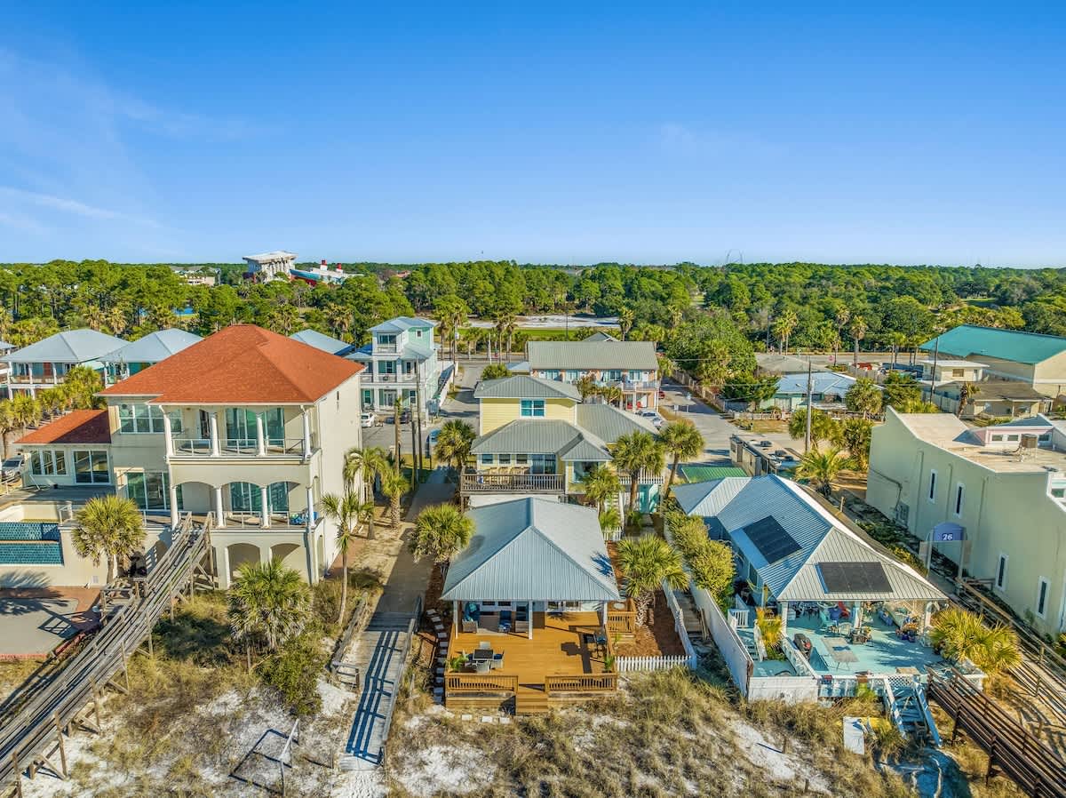 9620 Beach Blvd – Aerial view of beach houses with palm trees and sandy paths between them.