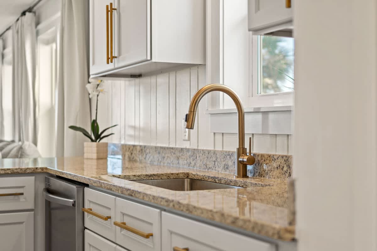 9620 Beach Blvd – Modern kitchen with granite countertops, stainless steel dishwasher, sink, and a potted orchid on the counter.