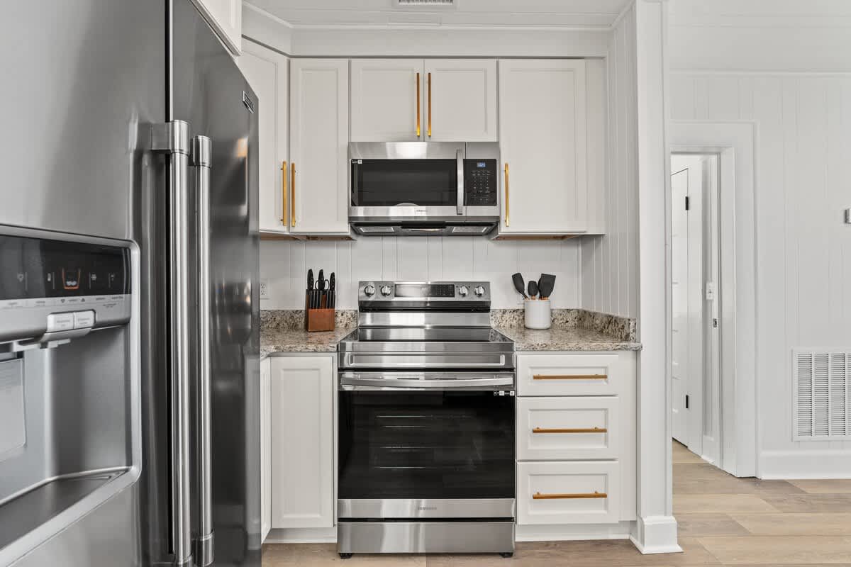 9620 Beach Blvd – Modern kitchen with stainless steel appliances, granite countertops, and white cabinetry.