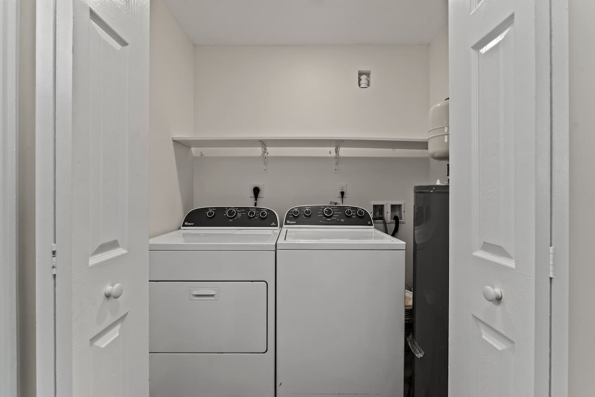9620 Beach Blvd – Laundry room with a washer and dryer, shelving, and utility connections.