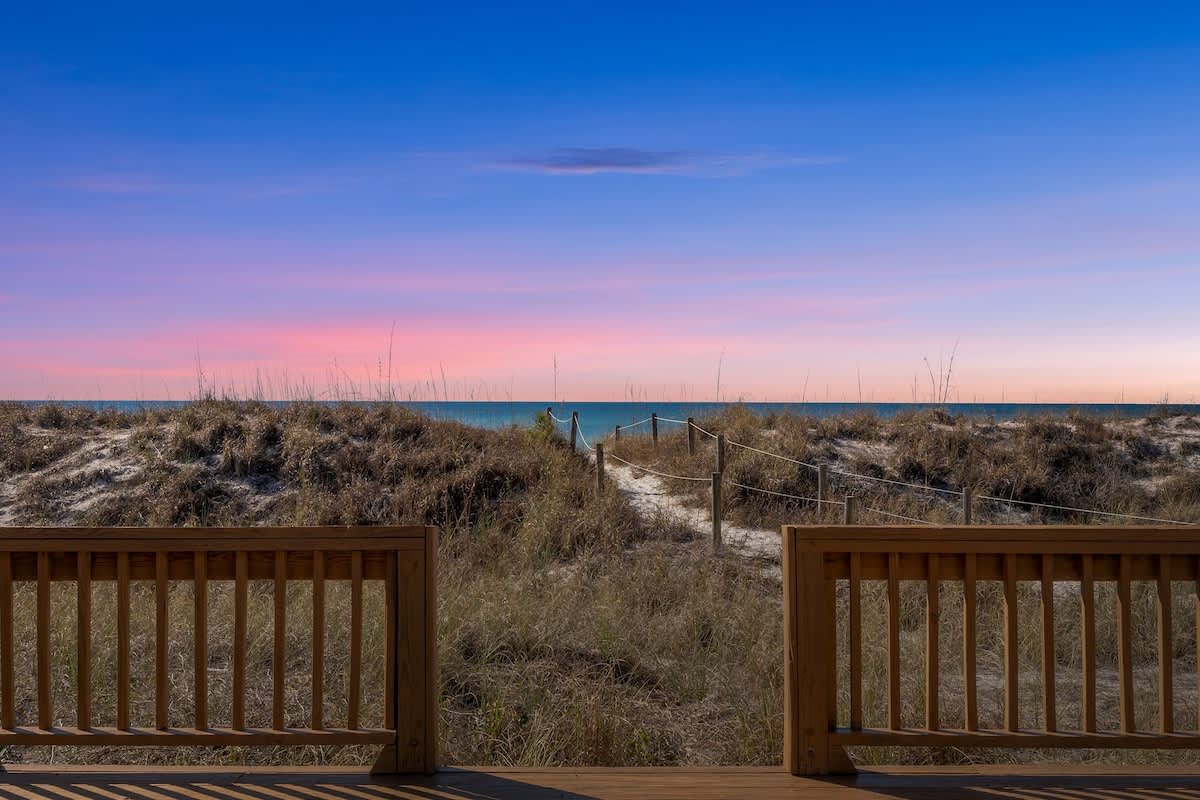 9620 Beach Blvd – View of beach pathway through dunes, with ocean and colorful sky in the background.